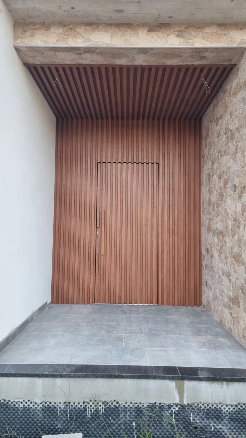 Entrada revestida a ripado de alumínio imitação madeira no teto e nas paredes, com a porta integrada