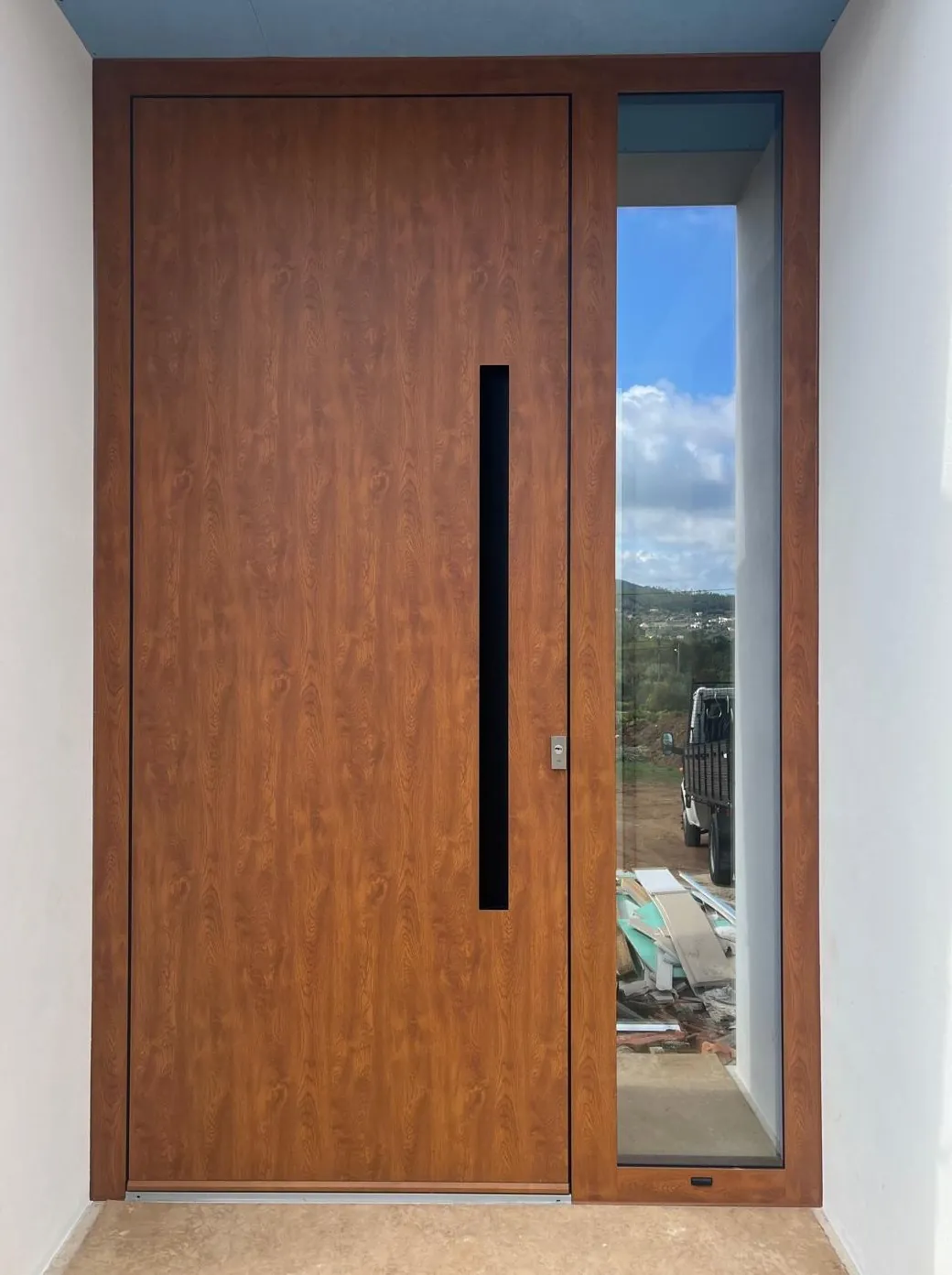 Porta em alumínio com acabamento imitação madeira, puxador embutido vertical e vidro lateral fixo