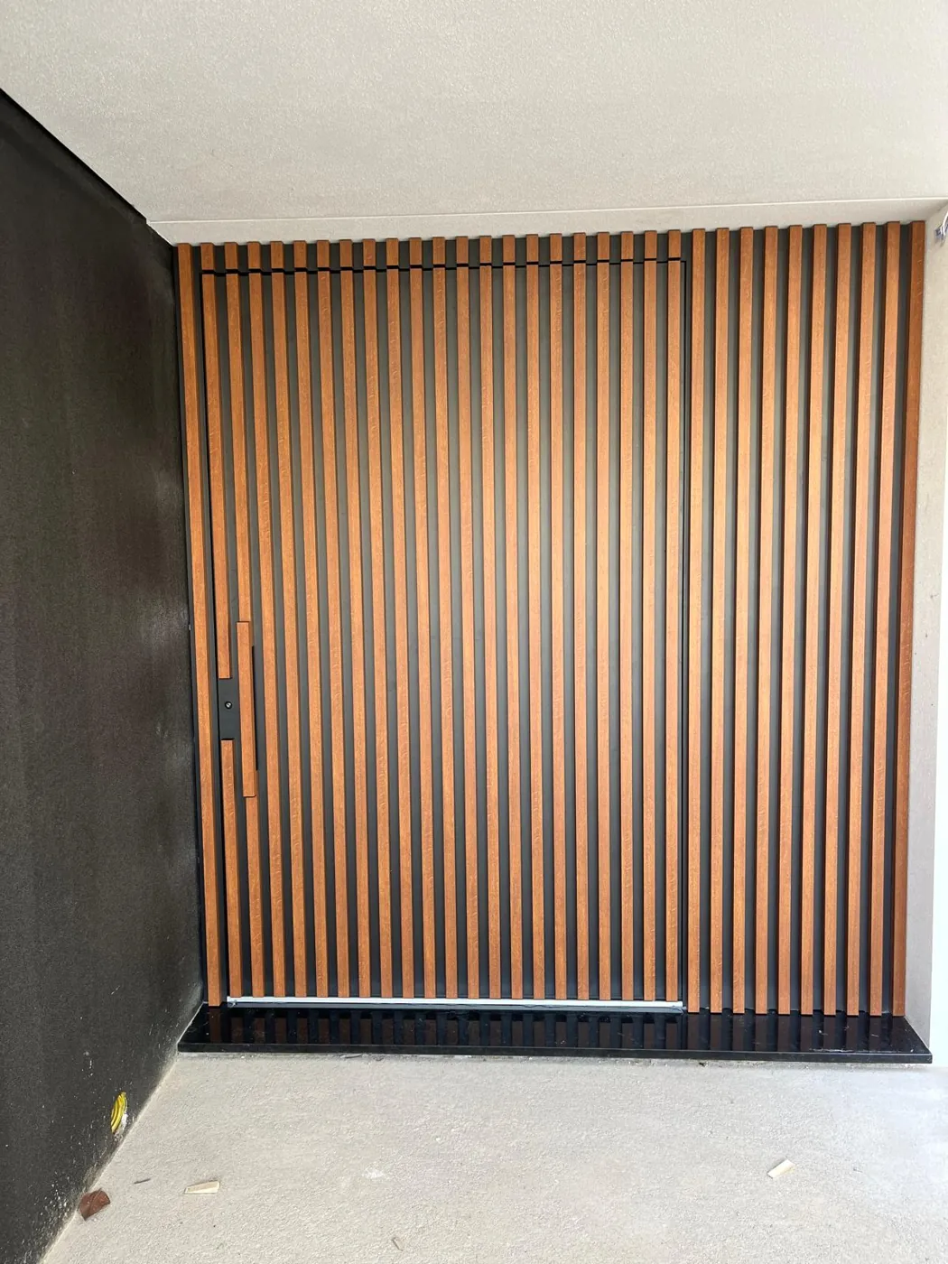 Porta oculta num painel ripado de alumínio imitação madeira que cobre toda a parede de entrada